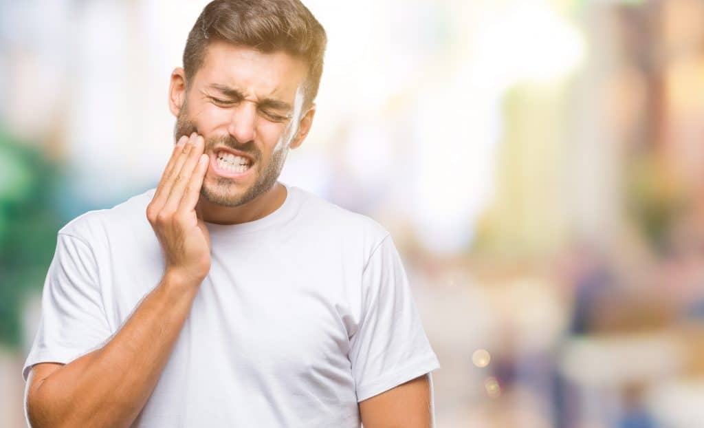Young handsome man over isolated background touching mouth with hand with painful expression because of toothache or dental illness on teeth. Dentist concept.